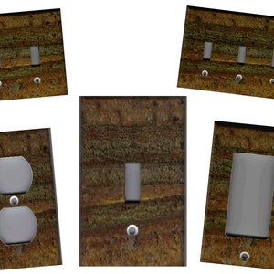 May include: Set of five light switch and outlet covers featuring a rustic woodgrain pattern with brown, green, and gold tones.