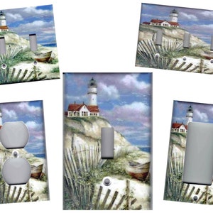 May include: Set of five light switch covers featuring a lighthouse on a sandy beach with a wooden fence and a boat in the foreground. The covers are available in single, double, and triple switch configurations.