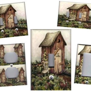 May include: Set of five light switch and outlet covers featuring a rustic outhouse with a sign that reads "Out of Order". The outhouse is surrounded by a garden with flowers and a small chair.