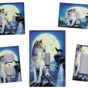 May include: A set of light switch and outlet covers featuring a wolf howling at the moon in a blue and purple night sky. The wolf is white and gray with a black nose and eyes. The moon is full and bright. The background is a dark blue with stars.