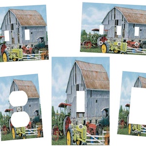 May include: A set of light switch and outlet covers featuring a vintage illustration of a red barn with a rusty metal roof, surrounded by tractors and farm equipment. The barn is painted a light blue with white trim. The background is a blue sky with white clouds.