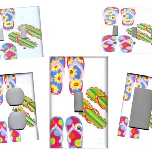 May include: Set of six light switch and outlet covers featuring a colorful flip-flop design. The covers are white with a variety of flip-flops in pink, blue, green, and yellow.