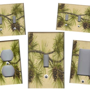 May include: Set of five light switch and outlet covers featuring a pine tree design with pine cones. The covers are beige with a vintage look and have a green pine tree design with brown pine cones.