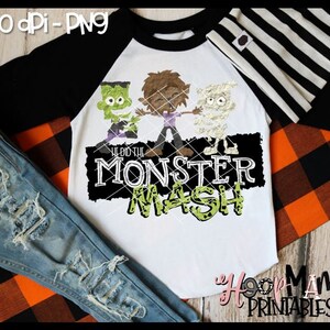 May include: A white long-sleeved shirt with black raglan sleeves. The shirt has a black and white striped hat on top. The shirt has a graphic of three cartoon monsters with the text "We Did The Monster Mash" in green and black.