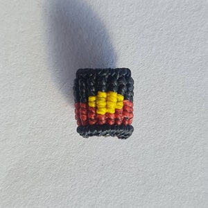May include: A small, black, red and yellow woven bead with the Aboriginal Australian flag design.