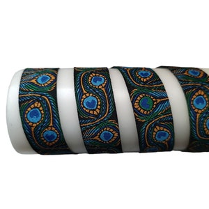 Op de afbeelding: Close-up van een zwart lint met een pauwenveerpatroon in tinten blauw, groen en goud.