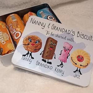 May include: A white metal tin with a colourful illustration of biscuits with faces. The text on the tin reads "Nanny & Grandad's Biscuits" and "To be shared with".  The names "Nanny", "Grandad", "Kerry", and "Jade" are written below the biscuits.