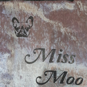 May include: A light pink velvet throw blanket with a black and white image of a French Bulldog and the text "Miss Moo" in black glitter.