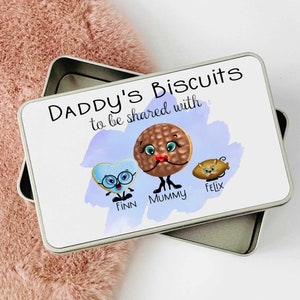 May include: White metal tin with a blue watercolor background and the text "Daddy's Biscuits to be shared with..."  Three cartoon biscuits are shown with the names "Finn", "Mummy", and "Felix" written below them.