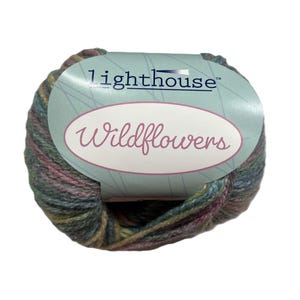 May include: A ball of Lighthouse Wildflowers yarn in shades of green, pink, and brown. The yarn is wrapped with a label that reads "lighthouse" and "Wildflowers" in a script font. The yarn is suitable for knitting and crochet projects.