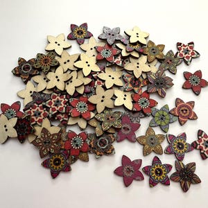 May include: A collection of wooden flower-shaped buttons in various colors and patterns. Some are plain wood, while others feature intricate designs in red, brown, green, and purple. Each button has two or four holes for sewing.