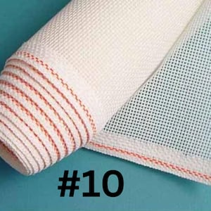 May include: Rolled white canvas with a grid pattern, featuring red stitching along the edges. The number "#10" is printed in black on the bottom. This material is likely used for crafting or needlepoint projects.