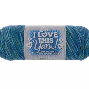 May include: A skein of variegated yarn in shades of blue, teal, and green. A paper label wraps around the centre, featuring the text I LOVE THIS YARN! SUPER SOFT... SUPER SAVINGS! PRINT, surrounded by small heart icons on a light grey background.