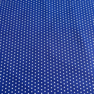 May include: Close-up of a blue fabric with a white polka dot pattern. The dots are evenly spaced across the surface. The fabric appears to be a medium weight material, suitable for various sewing projects.