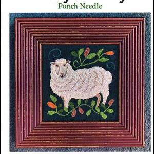 Op de afbeelding: Een vierkant punch needle kunstwerk met een wit schaap op een donkere achtergrond, omringd door groene en oranje bladmotieven. Het kunstwerk zit in een donkerrode, verweerde houten lijst. De tekst Punch Needle staat bovenaan.