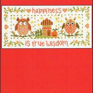 May include: Cross-stitch pattern with the text "OWL WISDOM" and "happiness is true Wisdom." The design features two owls, a house, and a pumpkin. The background is white with floral and heart accents, set against a red background.