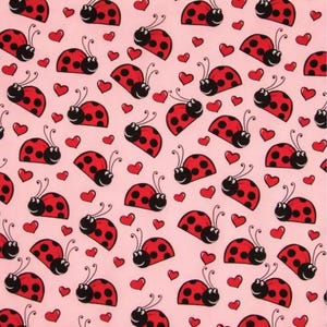 Pode incluir: Padrão repetitivo de joaninhas vermelhas com pintas pretas e corações vermelhos sobre um fundo rosa claro. As joaninhas têm antenas pretas e rostos sorridentes. Adequado para tecido ou papel de parede.