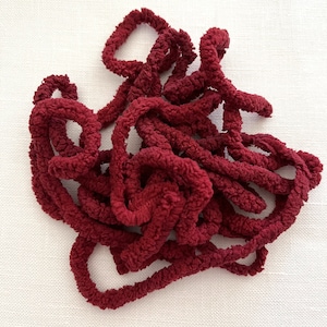 May include: A pile of burgundy-colored fuzzy yarn, perfect for crocheting or knitting.