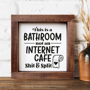 Letrero de baño: Este es un baño, no un cibercafé. Arte de baño dividido y de mierda. Regalo de inauguración de la casa. Reglas de alquiler a corto plazo.