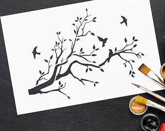 May include: A black and white illustration of a tree branch with leaves and birds on a white paper. Paintbrushes and paint pots are visible on a black surface. The artwork is likely for home decor or art projects.