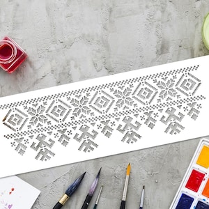 Puede incluir: Un esténcil blanco con un patrón geométrico gris de copos de nieve y diamantes. El esténcil está sobre una superficie gris con pinceles, acuarelas y un pequeño recipiente de pintura roja.