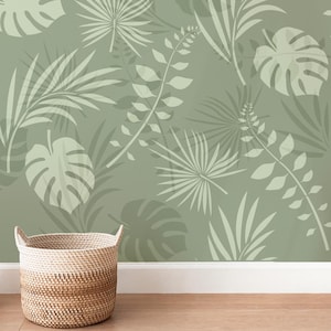 Könnte beinhalten: Eine grüne Tapete mit einem sich wiederholenden Muster aus hellgrünen tropischen Blättern. Die Tapete ist in einem Raum mit einem Weidenkorb im Vordergrund zu sehen.