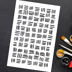 Op de afbeelding: Een wit papier met een herhalend patroon van zwarte, handgetekende lijnen. Het kunstwerk is omgeven door penselen en verfpotten op een zwart oppervlak, wat wijst op een kunst- of knutselthema.