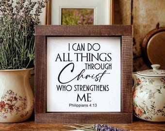May include: A framed wooden sign with the text "I CAN DO ALL THINGS THROUGH Christ WHO STRENGTHENS ME" from Philippians 4:13. The sign is surrounded by decorative items, including a vase of lavender and a floral-patterned teapot.