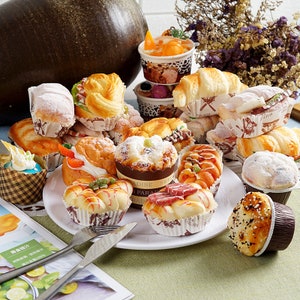May include: An assortment of miniature bakery goods, including pastries, cakes, and breads, displayed on a white plate. The pastries are decorated with icing, sprinkles, and chocolate.