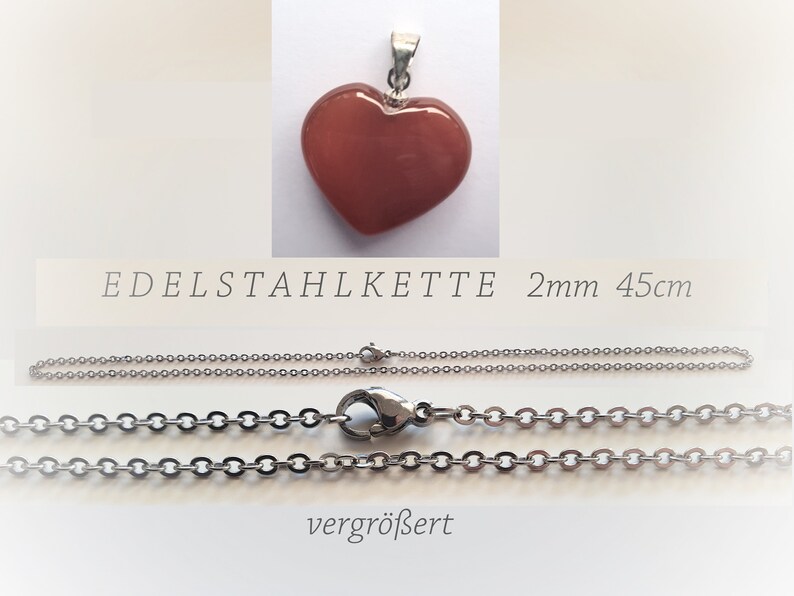 May include: A red heart-shaped pendant with a silver chain. The chain is 45 cm long and 2 mm wide. The text "EDELSTAHLKETTE 2mm 45cm" is visible below the pendant. The chain is shown in two views, one with the clasp closed and one with the clasp open.