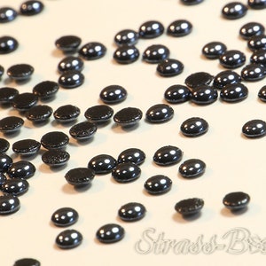 May include: A scattering of black, round, flat-backed rhinestones with a shiny, metallic finish.