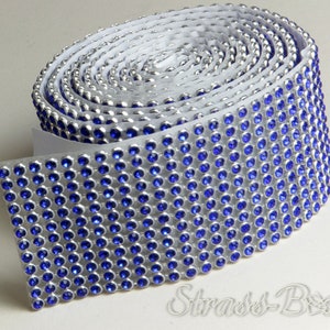 Könnte beinhalten: Rolle mit blauem Strassbesatz mit silberner Rückseite. Der Besatz ist aufgerollt und die Kleberückseite ist sichtbar.