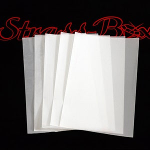 Könnte beinhalten: Ein Stapel aus fünf weißen, durchscheinenden Papierblättern. Die Blätter sind in der Mitte gefaltet und in Form eines Fächer angeordnet. Die Blätter liegen auf einem schwarzen Hintergrund.