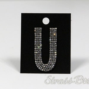 May include: A pair of silver earrings shaped like the letter U, made of small clear rhinestones.