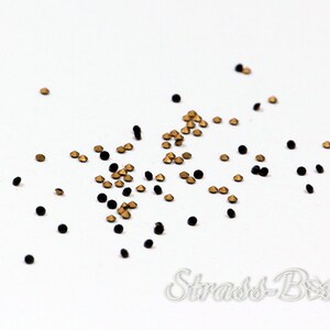 May include: Scattered black and gold rhinestones on a white background.