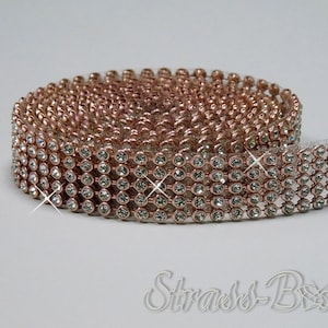 Puede incluir: Un rollo de ribete de strass de oro rosa con strass transparentes. El ribete está hecho de metal y tiene un acabado brillante.