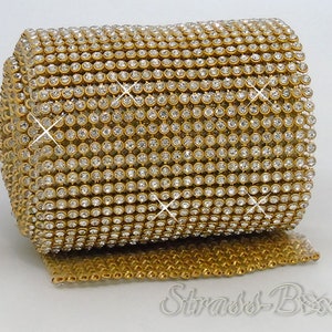 Op de afbeelding: Een rol gouden strassbies met heldere strasssteentjes. De bies is gemaakt van een gaasmateriaal en is perfect om knutselwerk en decoraties met glitter te versieren.