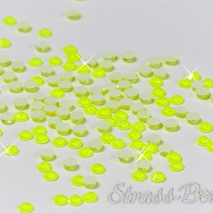 Può includere: Una spolverata di strass rotondi di colore giallo neon brillante con retro adesivo. Gli strass sono rotondi e hanno una superficie trasparente e sfaccettata.