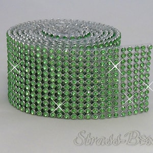 May include: A roll of green rhinestone trim with silver settings. The trim is made of small, round rhinestones that are arranged in a grid pattern.