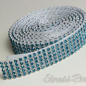 May include: A roll of silver trim with turquoise rhinestones. The trim is rolled up and the rhinestones are visible on the outside of the roll.