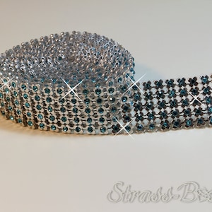 Könnte beinhalten: Eine Rolle silberne Strass-Borte mit türkisblauen Strasssteinen. Die Borte ist in einem Rastermuster angeordnet und eignet sich perfekt zum Verzieren von Bastelarbeiten und Dekorationen.