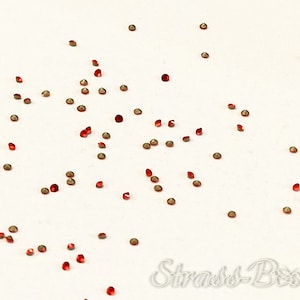 Könnte beinhalten: Rote und goldene Strasssteine auf weißem Hintergrund verstreut.