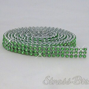 May include: A roll of green rhinestone trim with a silver backing. The trim is made of small, round rhinestones that are set close together.