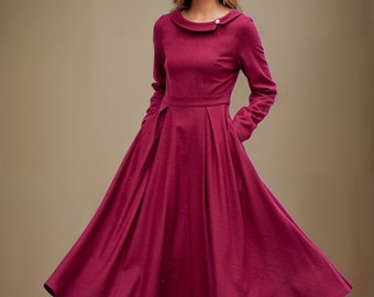 May include: A long-sleeved, burgundy dress with a collared neckline and a button detail on the shoulder. The dress has a fitted bodice and a full skirt.