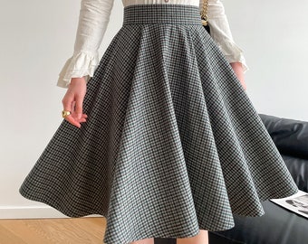 May include: A white long-sleeved blouse with a ruffled collar and button closure, paired with a green and black plaid skirt.