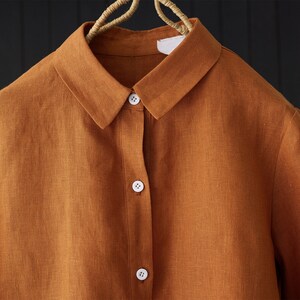 May include: A rust-colored linen shirt with a button-up front and long sleeves.