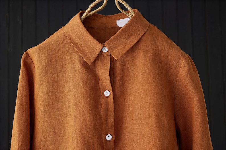 May include: A rust-colored linen shirt with a button-up front and long sleeves.