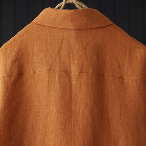 May include: A rust-colored linen shirt with a button-down collar and long sleeves.
