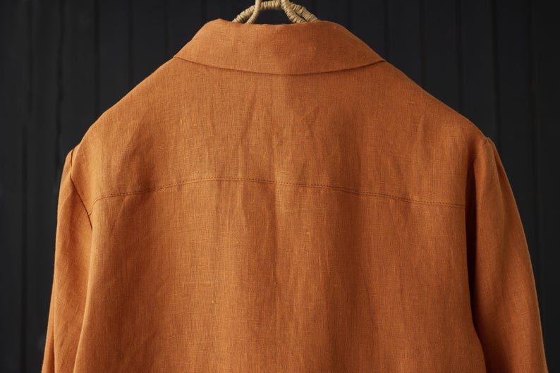 May include: A rust-colored linen shirt with a button-down collar and long sleeves.
