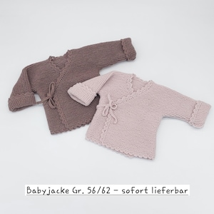 Könnte beinhalten: Zwei langärmelige Babyjacken mit Wickelverschluss, eine in Dunkelbraun und eine in Hellrosa. Beide haben eine Strickstruktur, gewellte Ränder und eine seitliche Bindung. Der Text "Babyjacke Gr. 56/62 - sofort lieferbar" ist zu sehen.